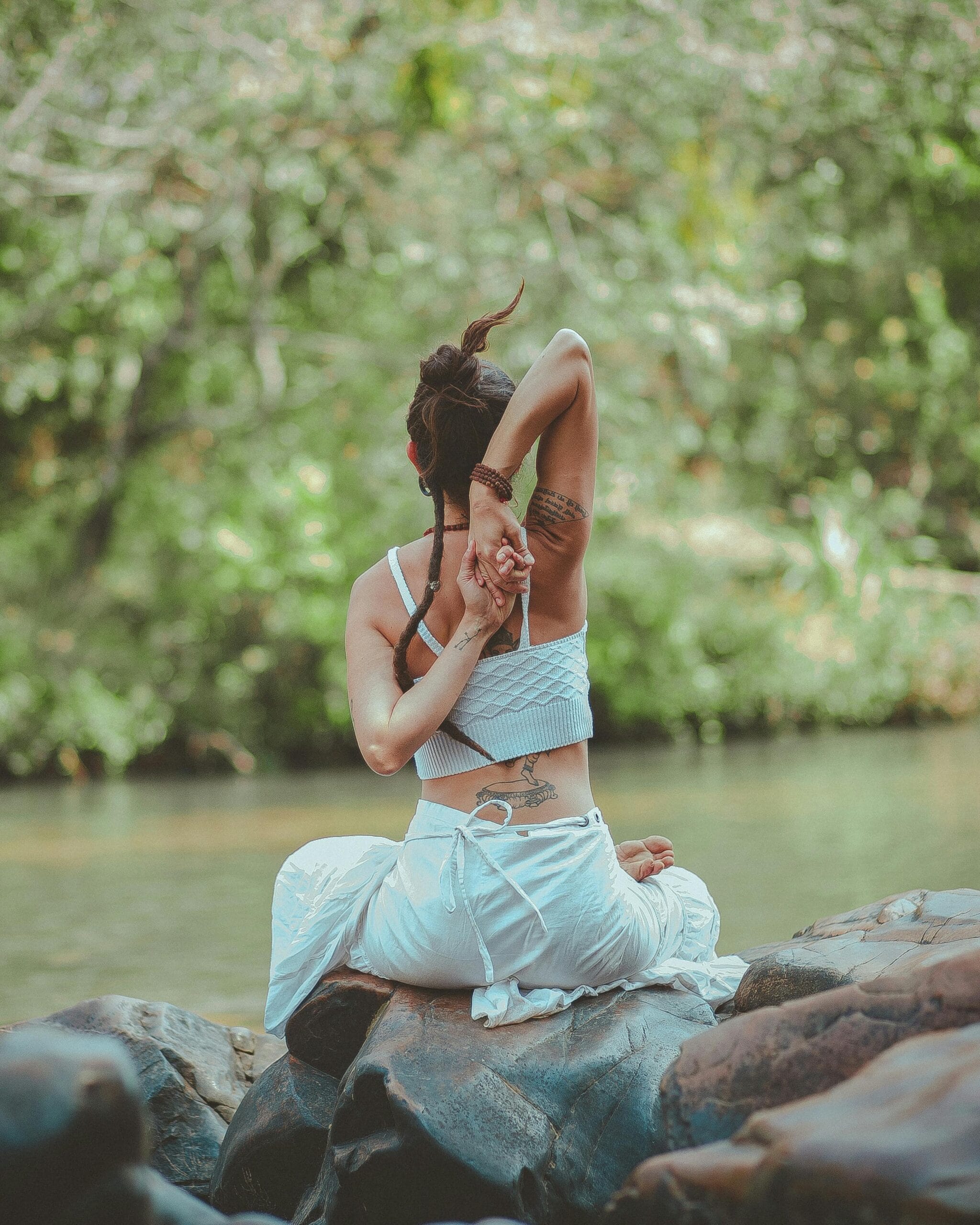 Une yogi sur des rochers au bord de la rivière pratique le yoga (thérapie holistique)